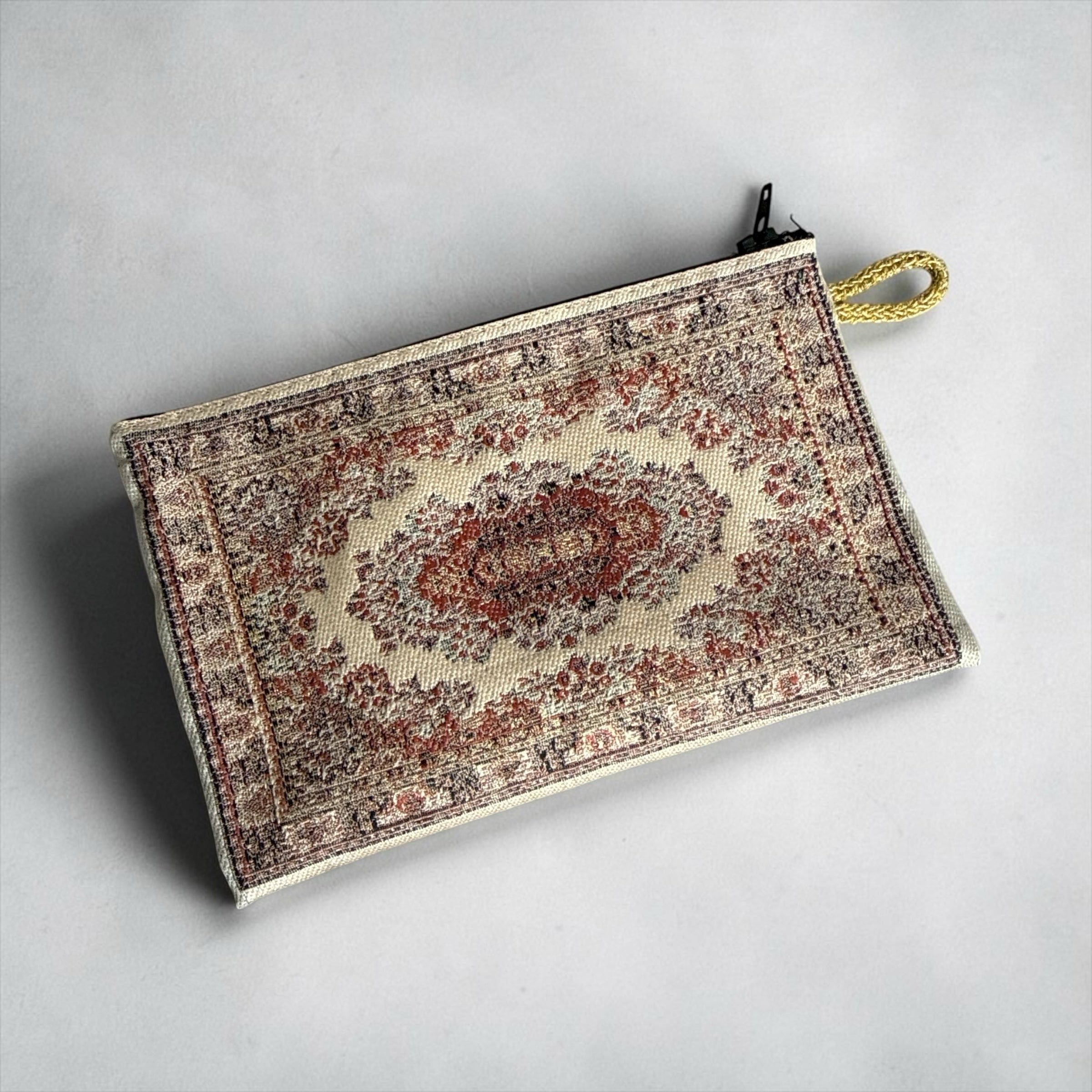 Niomes Boutique woven tapestry accessory pouch with intricate Persian rug pattern in earthy red and beige tones.